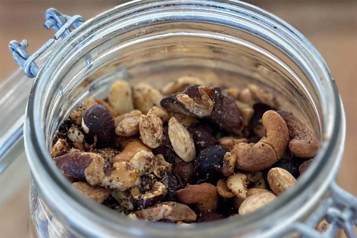 Mélange de noix, noisettes et noix de cajou avec huile d’olive et épices mexicaines avant cuisson au air fryer.