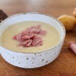 Soupe de pommes de terre crémeuse garnie de fines lanières de jambon fumé, servie chaude dans un bol.