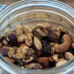 Mélange de noix, noisettes et noix de cajou avec huile d’olive et épices mexicaines avant cuisson au air fryer.